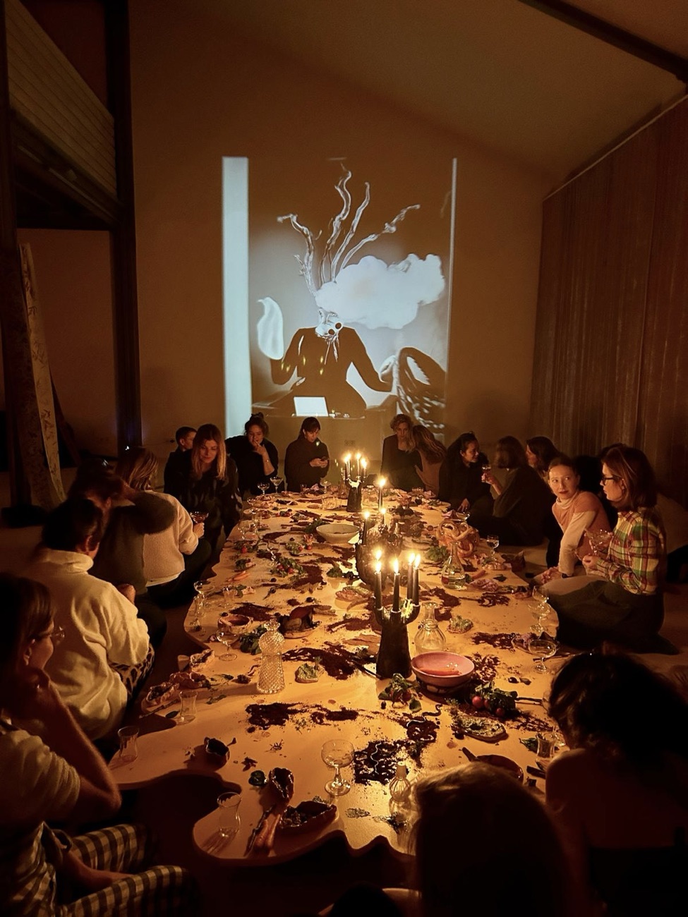 A community gathered around a long candlelit banquet table